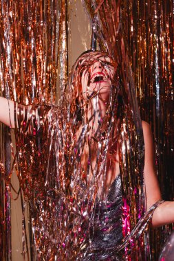 Mutlu kadın yeni yılı kutluyor. Gümüş parıltılı elbiseli güzel bir kadın yılbaşı partisinde eğleniyor. Tatil kutlaması. Genç kız mutluluk ve şaşkınlık duygularını ifade eder..