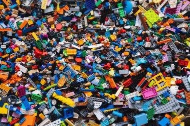 Karışık plastik inşaat tuğlalarının renkli arka planı oyuncakları. Birden fazla rengi olan küçük plastik bloklar, üst görünüm, yaşam tarzı fotoğrafı. Çocukların eğlencesi, çocukların eğitimi ve gelişimi.