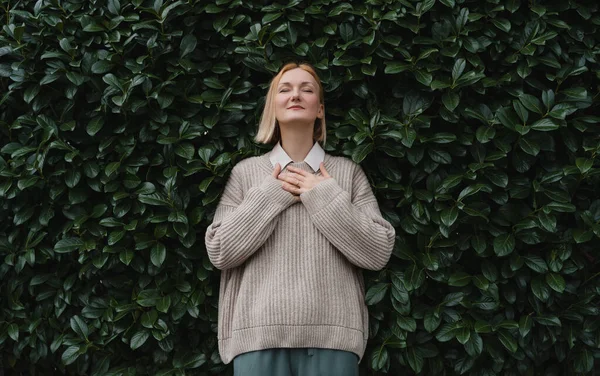 stock image Portrait of relaxed woman with eyes closed on background of green leaves wall. Concept of outside of office, Work-Life-Balance, Taking Break. Zen and balance people. Stability through mental health.