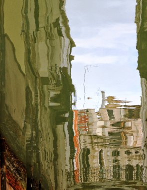 Yağmurlu bir günde yağmur birikintisindeki su birikintisindeki yansımanın dikey görüntüsü. 