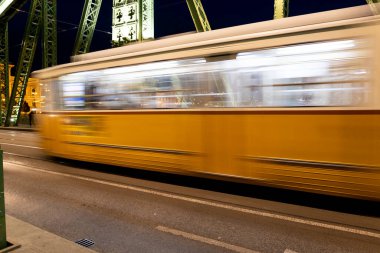 Bulanık sarı tren Macaristan 'daki köprüde hızla ilerliyor..