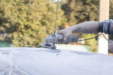 Araba tamircisinin elleri arabanın çatısını öğütüyor..