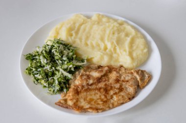 Lezzetli bir kahvaltı veya patates püresi, salatalı pirzola - yeşil soğan ve taze lahana, beyaz tabakta maydanoz.