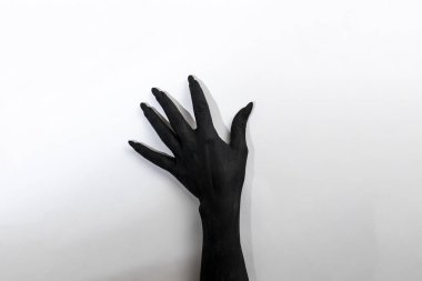 The black hand with long nails. Concept photo with woman hand painted in black paint  -  moving on wall clipart