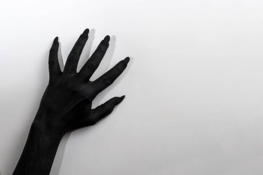 Uzun tırnaklı siyah el. Siyah boyayla boyanmış kadın resmi. Duvarda hareket ediyor.