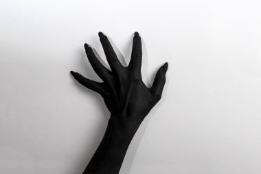 Uzun tırnaklı siyah el. Siyah boyayla boyanmış kadın resmi. Duvarda hareket ediyor.