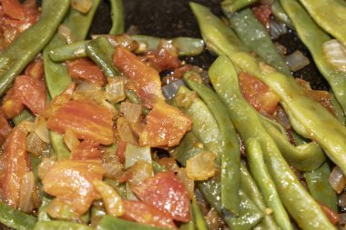 Domates ve soğanlı kızarmış yeşil fasulye. Yemekte fasulyeli lezzetli yemek ya da tavada öğle yemeği.