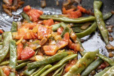 Domates ve soğanlı kızarmış yeşil fasulye. Yemekte fasulyeli lezzetli yemek ya da tavada öğle yemeği.