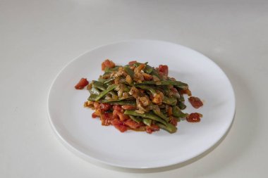 Domates ve soğanlı kızarmış yeşil fasulye. Yemekte fasulyeli lezzetli yemek ya da beyaz tabakta öğle yemeği.