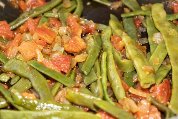 Domates ve soğanlı kızarmış yeşil fasulye. Yemekte fasulyeli lezzetli yemek ya da tavada öğle yemeği.