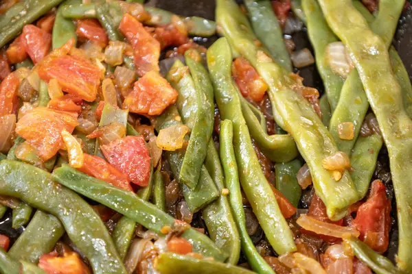Domates ve soğanlı kızarmış yeşil fasulye. Yemekte fasulyeli lezzetli yemek ya da tavada öğle yemeği.