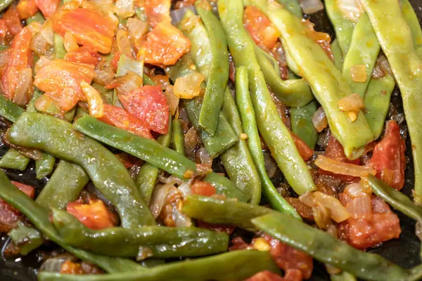Domates ve soğanlı kızarmış yeşil fasulye. Yemekte fasulyeli lezzetli yemek ya da tavada öğle yemeği.