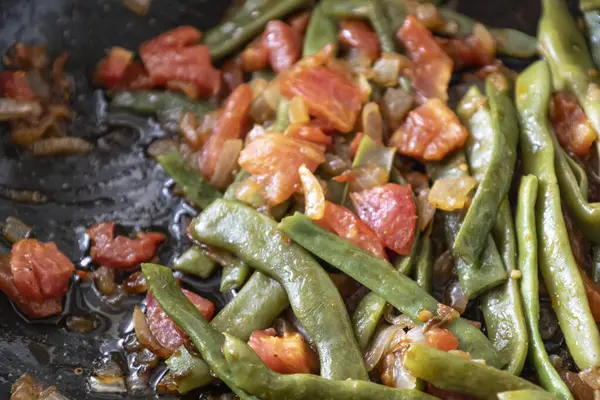 Domates ve soğanlı kızarmış yeşil fasulye. Yemekte fasulyeli lezzetli yemek ya da tavada öğle yemeği.