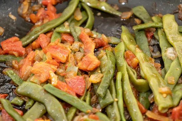Domates ve soğanlı kızarmış yeşil fasulye. Yemekte fasulyeli lezzetli yemek ya da tavada öğle yemeği.