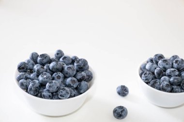 Yabanmersini lezzetli, sağlıklı ve lezzetli meyvelerdir. Beyaz kasede taze yaban mersini. Beyaz arka planda beyaz tabakta yabanmersini.