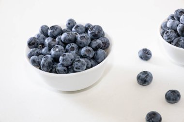 Yabanmersini lezzetli, sağlıklı ve lezzetli meyvelerdir. Beyaz kasede taze yaban mersini. Beyaz arka planda beyaz tabakta yabanmersini.