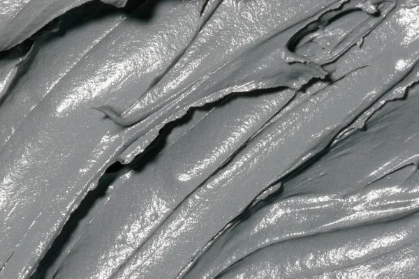 Cosmetic texture clay mask for face and body. Natural spa cosmetics. Dead sea mud gray background. Top view. Space for text.