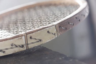 Eski ahşap tenis raketinin ayrıntıları. Teller, hasarlı ahşap çerçeve. Yumuşak ışıklar, bulanık ve yumuşak detaylar.