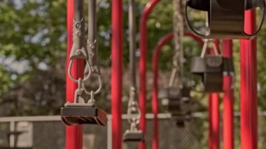Boş salıncaklar parkta yavaşça hareket ediyor. Yaz güneşli bir gün. Arka planda yeşil ağaçlar var. Kilitlenme. Karantina ve tecrit
