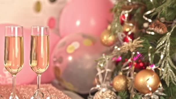 シャンパン お祝いの装飾 黄色と赤の電球とクリスマスツリーの装飾の2つのメガネとクリスマスライト — ストック動画