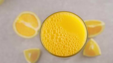 Bir bardak portakal suyunun üstüne köpük dök, meyve suyu bardağının yanında portakal dilimleri, üst manzara, yavaş çekim, kapat.