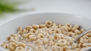 Spoon mixing round whole grain cereals with milk. Eating dry breakfast cereals for healthy breakfast. Close-up. Balanced meal. Child healthy growth concept. Slow motion.