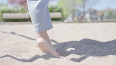 Parkta salıncakta sallanan çıplak ayaklı, tanınmaz bir anaokulu çocuğu. Mutlu çocuk bahar çocuk parkında eğleniyor. Çocukluk eğlence konsepti.