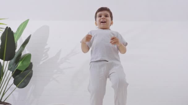 Sevimli Küçük Çocuk Beyaz Yatak Örtüsüyle Yatakta Zıplarken Eğleniyor Sağlık — Stok video