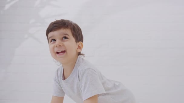 Sevimli Küçük Çocuk Beyaz Yatak Örtüsüyle Yatakta Gülüp Eğleniyor Mutlu — Stok video