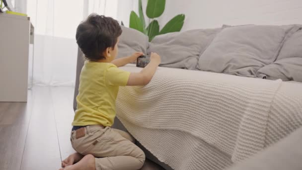 かわいい子供の男の子はスマートフォンで遊んで 漫画を見て自宅のリビングルームで一人で床に座って — ストック動画