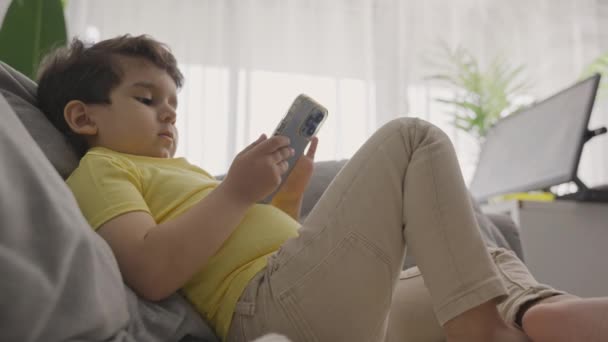 Vidám Fiú Megható Képernyőn Mobiltelefon Miközben Videojátékok Kanapén Otthon Élvezze — Stock videók