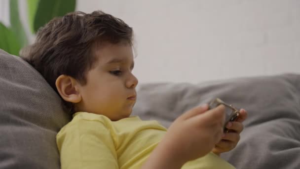 Sidovy Bedårande Barn Sitter Soffan Spela Online Spel Med Mobiltelefon — Stockvideo