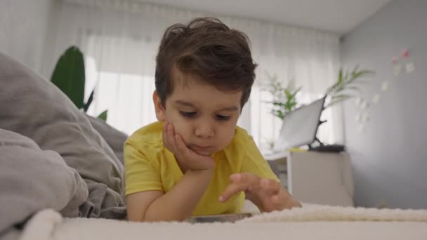 Αξιολάτρευτο Μικρό Παιδί Ξαπλωμένο Στον Καναπέ Αγγίζοντας Οθόνη Του Κινητού — Αρχείο Βίντεο