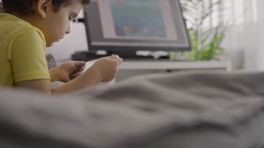 Sevimli küçük bebek modern cihaz akıllı telefon ekranında evde dinleniyor çizgi film izliyor, online oyunlar oynuyor. Cep telefonu kullanan modern teknoloji çocuğuna bağımlı.