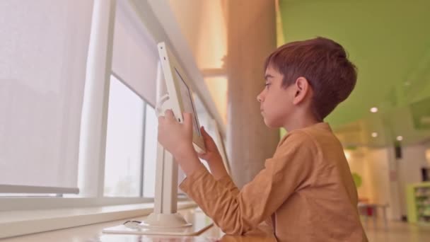 Roztomilý Školní Chlapec Hraje Dotykovou Obrazovku Aplikace Tabletu Uvnitř Koncept — Stock video