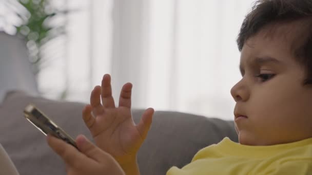 Anak Kecil Yang Manis Santai Sofa Menggunakan Aplikasi Elektronik Telepon — Stok Video