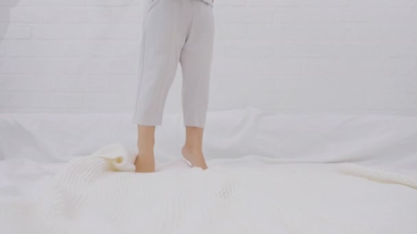 活跃的白人男孩在床上跳 早上腿在白色被褥上跳着 靠在腿上 幸福和自由的概念 慢动作 — 图库视频影像