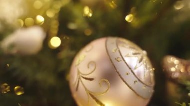 Peri arka planında parlak altın toplarla süslenmiş Noel ağacını kapatın. Odaklanmamış çelenk ışıkları, bokeh etkisi.