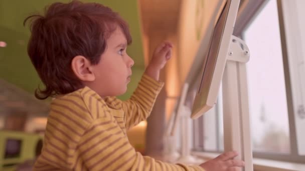 Lykkelig Lille Kaukasisk Dreng Smiler Ser Noget Digital Tablet Indendørs – Stock-video