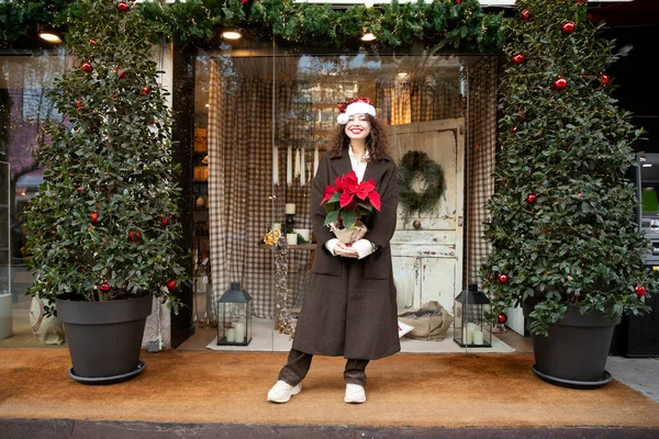 Christmas mood, full length model in coat and santa hat with poinsettia flower. christmas design
