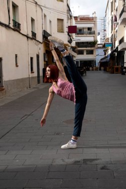 Model, güneşin altındaki binaların zemininde dans ediyor. İp içindeki sporcu kadın