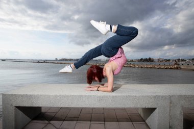 Model akrobat deniz kenarında yoga yapıyor. Kız amuda kalktı. Profesyonel spor.