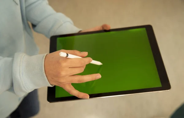Hands are holding a drawing tablet. Tablet with stis, green screen. Technology and communication concept. cropped view.