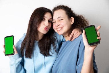 Yeşil ekranlı telefonu olan kızların portresi. Aletleri olan mutlu modeller