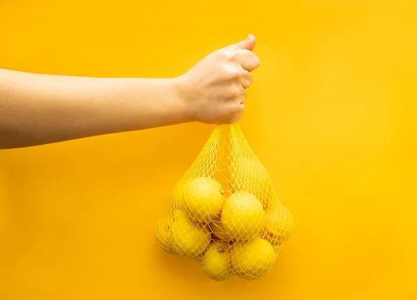 Sarı arka planda limonlar. Yakından bir avuç limon tutarken..