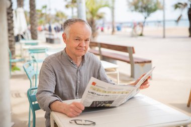 Emekli adam gazetede oturuyor.