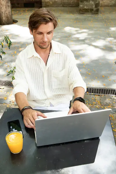 Güneşli şehir kafesinde çalış ve rahatla. İşte dizüstü bilgisayarı olan biri.