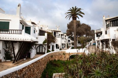 Menorca, İspanya 'da bir köyde geleneksel beyaz evler ve palmiye ağaçları 03.08.2025