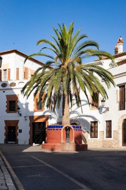 İspanya, Sitges 'de palmiye ağaçları ve beyaz evleri olan güneşli bir meydan. 30.06.2025