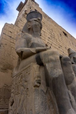 The statue of Ramses II standing at the entrance of the Temple of Luxor surrounded by ancient columns in Egypt clipart